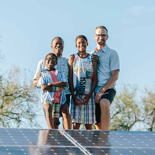 family on roof next to solar panels