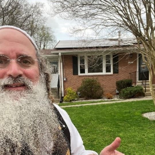 man in front of home with solar panel