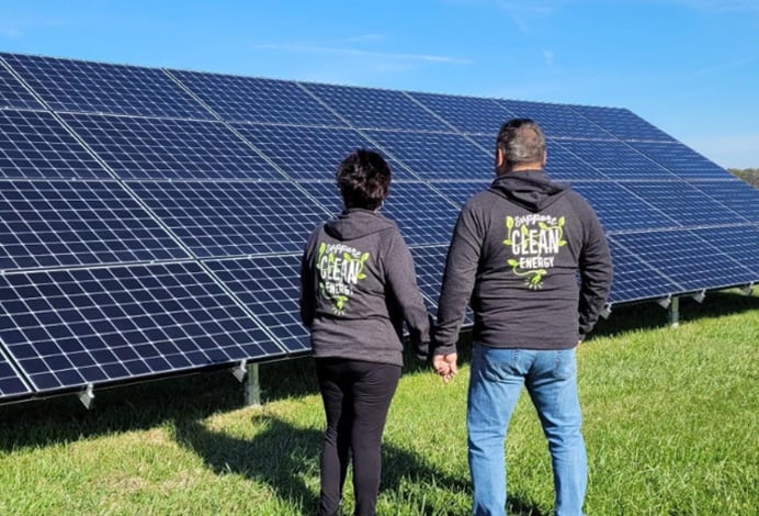 couple holding hands in front of solar panel