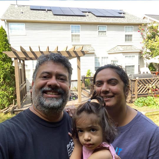 happy family in front of home with solar